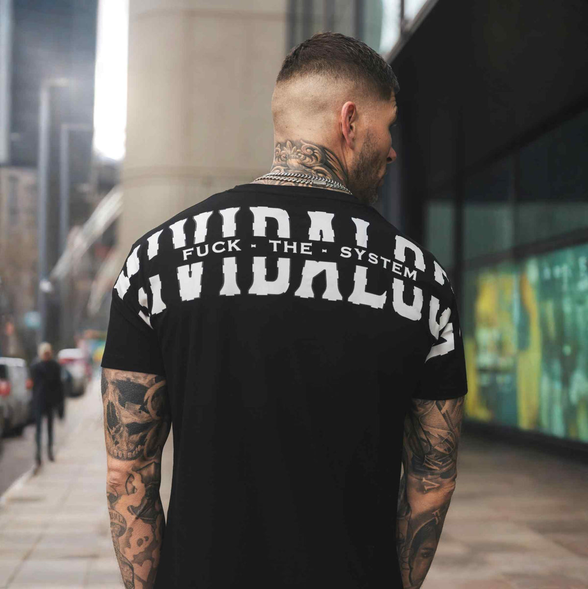 Rückseite des schwarzen FTS T-Shirts mit weißem Mi Vida Loca Rückenprint, getragen von Model auf der Straße