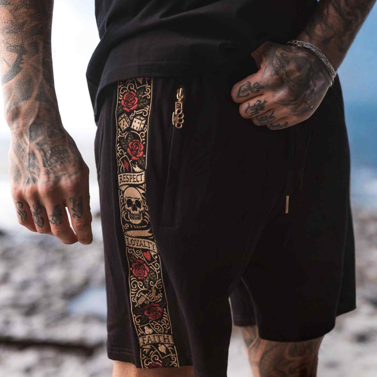 Close-up of the black LFR jogger shorts worn, embroidered band and zip with MVL logo pendant