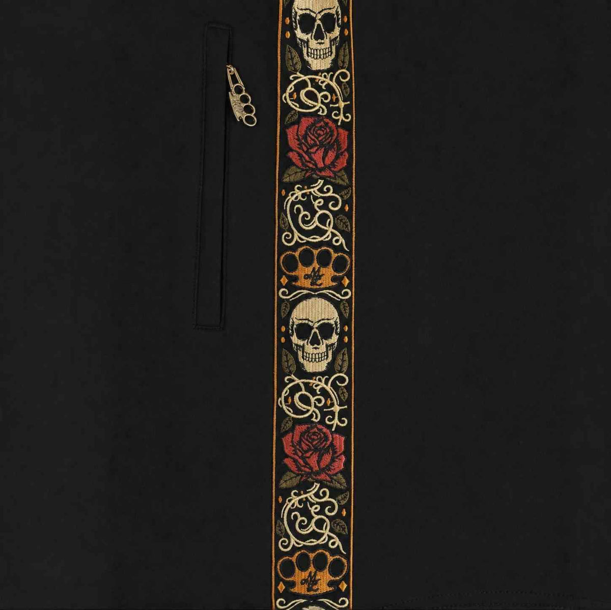 Nahaufnahme des gestickten Calavera Bands mit Totenköpfen, Rosen und MVL-Logo neben dem Taschenreißverschluss