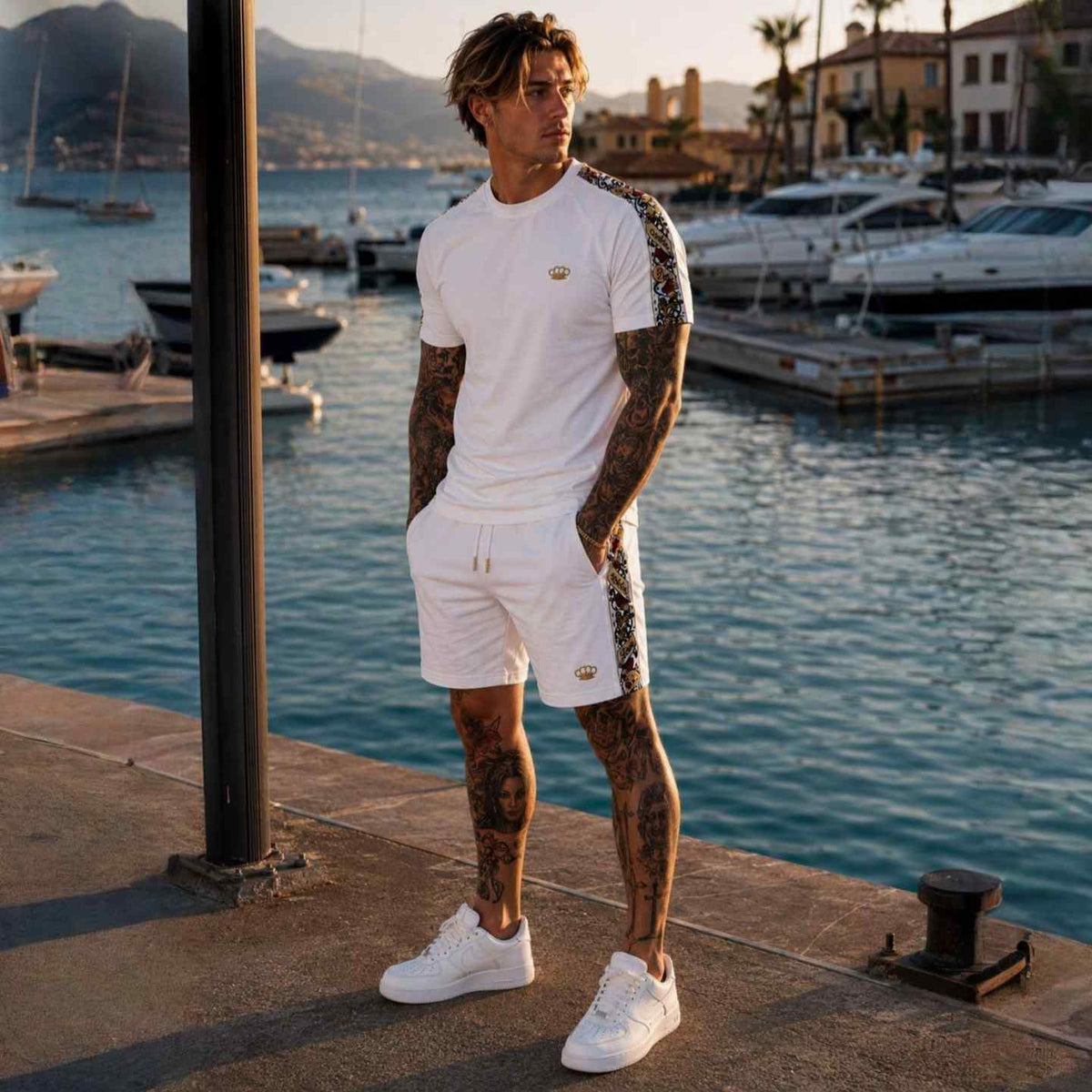 Savage ornate jogger shorts wit gedragen door model met wit T-shirt op de kade, handen in de zakken