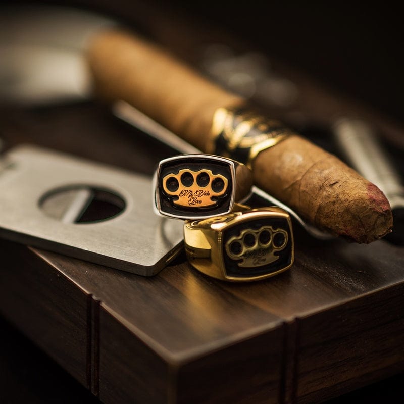 Zilveren en gouden MVL zegelring naast een sigaar en sigarenknipper op hout