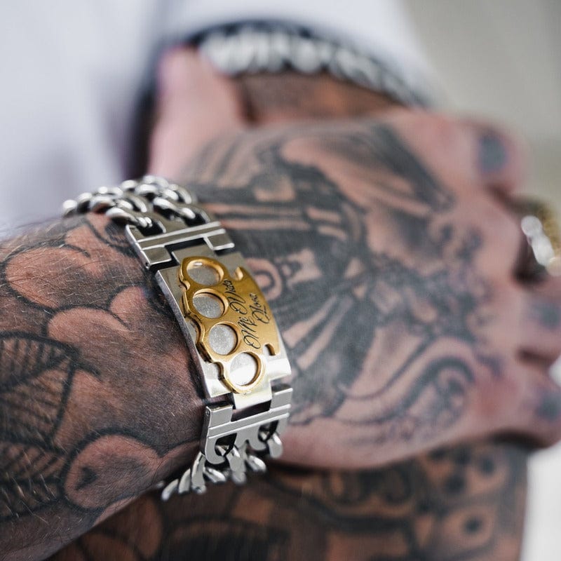 Sølv MVL armbånd med guld MVL logo om et tatoveret håndled, nærbillede