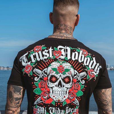 Trust nobody flower skull T-Shirt schwarz, getragen von Model, Rückseite mit Rückenprint am Wasser