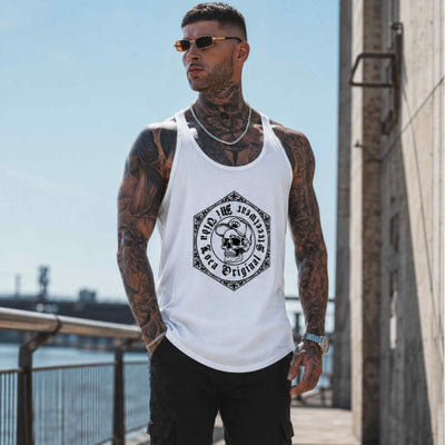 Tattooed model in sunglasses wearing the white MVL Original streetwear tank top by the water